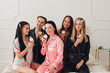 © Вячеслав Косько - Happy pretty women in sleepwear sitting on the edge of the bed and holding cupcakes. Friendship and happiness concept