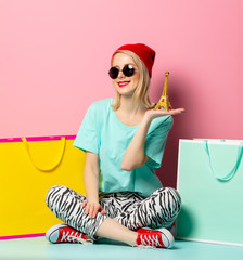 Canvas Print - Style woman in sunglasses with shopping bags and little Eiffel tower on pink background