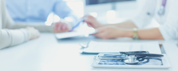 Doctor in clinic asking senior woman in wheelchair for a signature