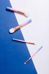 Wall Mural - Set of makeup brushes on blue and white colored composed background. Top view point, flat lay.