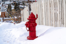 Vibrant Red Fire Hydrant Against Snow And Hill Homes At Park City Utah In Winter