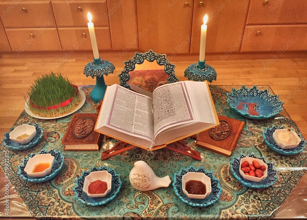 High Angle View Of Koran Amidst Foods And Lit Candles On Rug During Nowruz - obrazy, fototapety, plakaty 