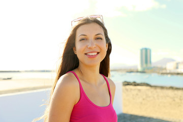 Wall Mural - Portrait of beautiful young woman with sunglasses on her head on seaside town looking at camera in windy day