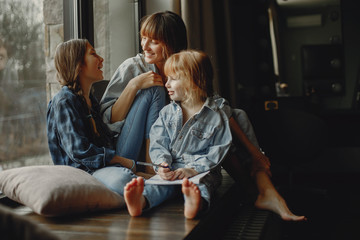 Wall Mural - Beautiful mother with two daughters. Family sitting in the room near window