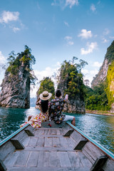 couple traveling by boat exploring epic limestone cliffs in huge lake in Khao Sok National Park, Chiew lan lake, Thailand