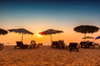 Sun umbrellas with lounge chairs at sunset on a tropical sunny beach in GOA, India