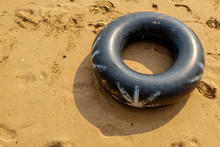 High Angle View Of Black Tire On Sand At Beach During Sunny Day