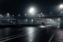 Foggy Misty Night Road And Overhead Pedestrian Bridge Illuminated By Street Lights