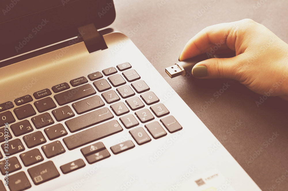Hand by connecting a USB flash drive to a laptop. on a black background ...