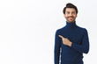 Confident, good-looking happy smiling caucasian man with bristle in stylish high neck sweater, proudly pointing left and look camera, recommend promo, advertise product, white background