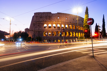 Fototapete - Rome, Italy - Jan 2, 2020: Colosseum at night with colorful blurred traffic lights