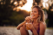 © bnenin - Close-up portrait of a beautiful happy young woman drinking on a beach. Summer vacation concept.