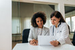 © bnenin - Medical exam. Portrait of a beautiful female doctor and patient looking at test results.