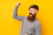 Redhead man with long beard over isolated yellow background celebrating a victory