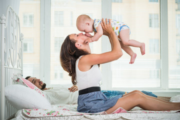 Side view of happy young parents chatting with their charming half year old baby. The concept of a happy family and healthy children