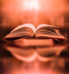 Poster - an ancient book that opens with magic, the magic light in the darkness on the wooden table, by the b