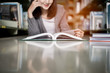 Woman reading a book in library. Portrait of college girl reading book in library