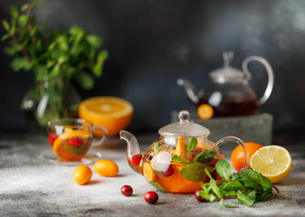 Wall Mural - Fruit tea with mint, oranges and cranberry on dark stone background. A cup of hot tea