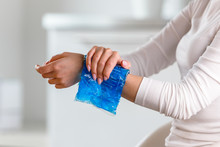 Woman Applying Cold Compress To A Her Painful Wrist Caused By Prolonged Work On The Computer, Laptop, Copy Space. Carpal Tunnel Syndrome, Arthritis, Neurological Disease. 