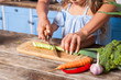 Closeup of mother and child chopping vegetable with knife on board, cooking healthy breakfast together, preparing vegetarian salad in kitchen, fresh vegetables on table, vegan food, diet nutrition