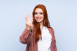 © luismolinero - Redhead teenager girl over isolated blue background happy and counting three with fingers