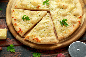 Wall Mural - Garlic cheese pizza on wooden board with herbs.