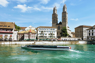 Wall Mural - River boat at Limmatquai and Grossmunster Church in Zurich, Switzerland. People on the background