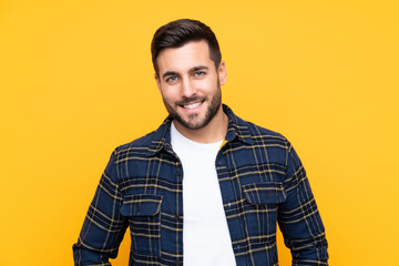 Young handsome man with beard over isolated yellow background laughing