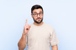 Young handsome man with beard over isolated blue background pointing with the index finger a great idea
