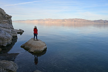 Young Woman In Red Sweater And Jeans Enjoying View Of Pyramid Lake, Nevada From Rock Formations On Coast On Late Winter Afternoon.