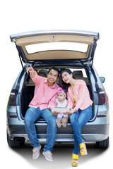 Wall Mural - Parents and child sitting behind the car