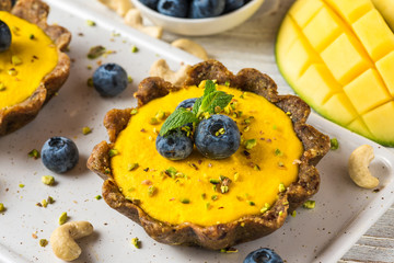 homemade raw mango cakes with fresh berries, pistachio and mint. healthy vegan gluten free food concept