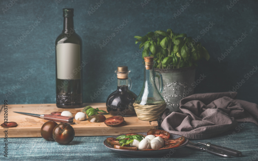Obraz na płótnie Food still life with oil bottles, mozzarella,  tomatoes and kitchen herbs in pot on kitchen table background w salonie