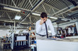 © Dusan Petkovic - Tired caucasian bearded supervisor in shirt and tie standing in printing shop In background are printing machines.