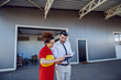 © Dusan Petkovic - Cheerful director showing to his female employee tasks for work that day. Director holding notebook and they are both looking at it. Printing shop exterior.