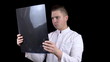 © Vital9c - A young man doctor checks the results of an MRI scan of a spine. A man examines an MRI image on a black background.