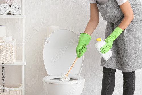 Cuadros en Lienzo Young woman cleaning toilet in bathroom