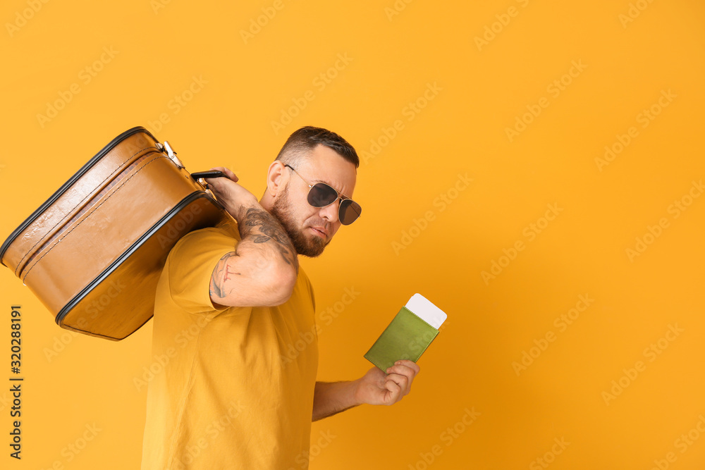 Male tourist with documents and luggage on color background