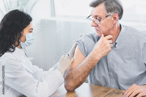 Fotomural Mexican doctor doing vaccination to elderly man