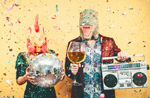 Crazy Couple Celebrating New Year Eve Wearing Chicken And Dinosaur T-rex Mask - Young Trendy People Having Fun Drinking Champagne And Listening Music With Vintage Boombox - Absurd And Holidays Concept