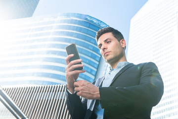 Wall Mural - young businessman looking at mobile phone in city