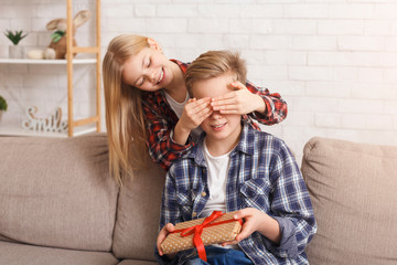 Wall Mural - Sister Covering Brother's Eyes Giving Birthday Gift Sitting At Home