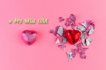 Concept of February 14 or Valentine's Day. Chocolate candy-a heart in a red wrapper and a torn wrapper from the candy, and pink bonbon. Pink background. My new love