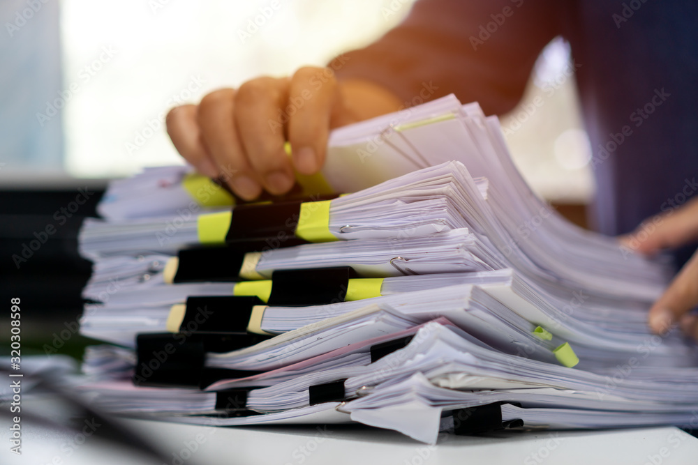 Stacks documents of paper files, Businessman hands working in messy bureaucracy and searching information on office, Accounting budget report file, arranging unfinished of paperwork on busy overwork - obrazy, fototapety, plakaty 