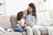 © Prostock-studio - Pregnant woman and little daughter having conversation at home