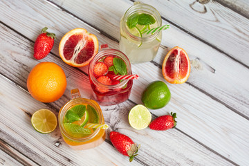  Summer drinks. Fresh freshes on a wooden background. View from above. Orange, lemon and strawberry fresh.