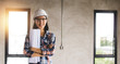 © khwanchai - portrait of engineer woman holding blueprint in construction site