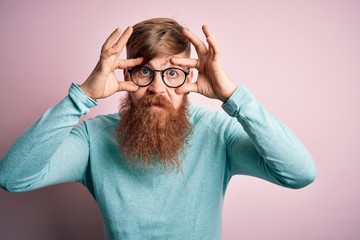 Wall Mural - Handsome Irish redhead man with beard wearing glasses over pink isolated background Trying to open eyes with fingers, sleepy and tired for morning fatigue