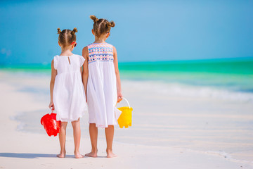 Little happy funny girls have a lot of fun at tropical beach playing together. Sunny day with rain in the sea