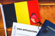 © mirsad - Flag of Belgium , visa application form and passport on table